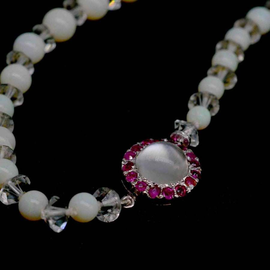 Early 20th Century opal bead necklace featuring ruby and moonstone clasp, showcasing milky hues and crystal accents.