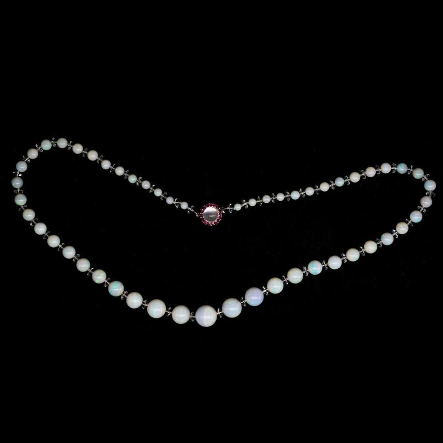 Early 20th century graduated opal bead necklace with ruby and moonstone clasp, showcasing colorful opal highlights.