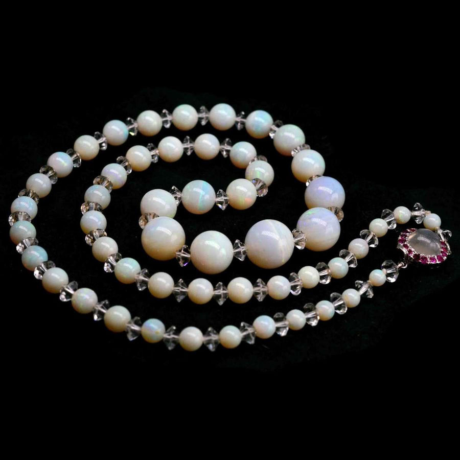 Early 20th Century graduated opal bead necklace with ruby and moonstone clasp, featuring rock crystal accents.
