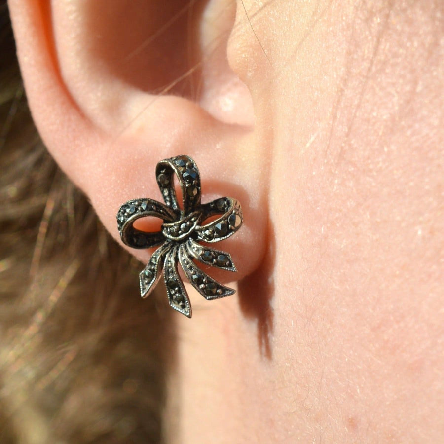 Edwardian silver marcasite bow earrings displayed on an ear, showcasing vintage elegance and intricate design.