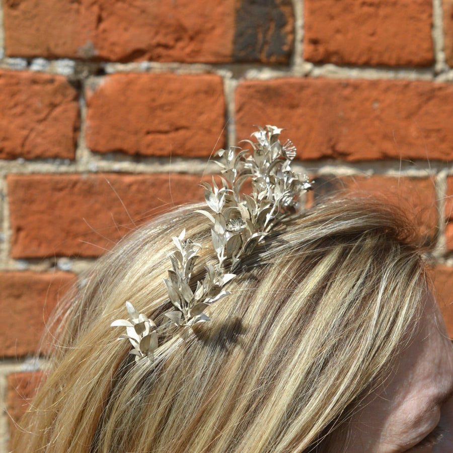 Mid 19th century Victorian silver leaf tiara worn in hair, against a brick background.