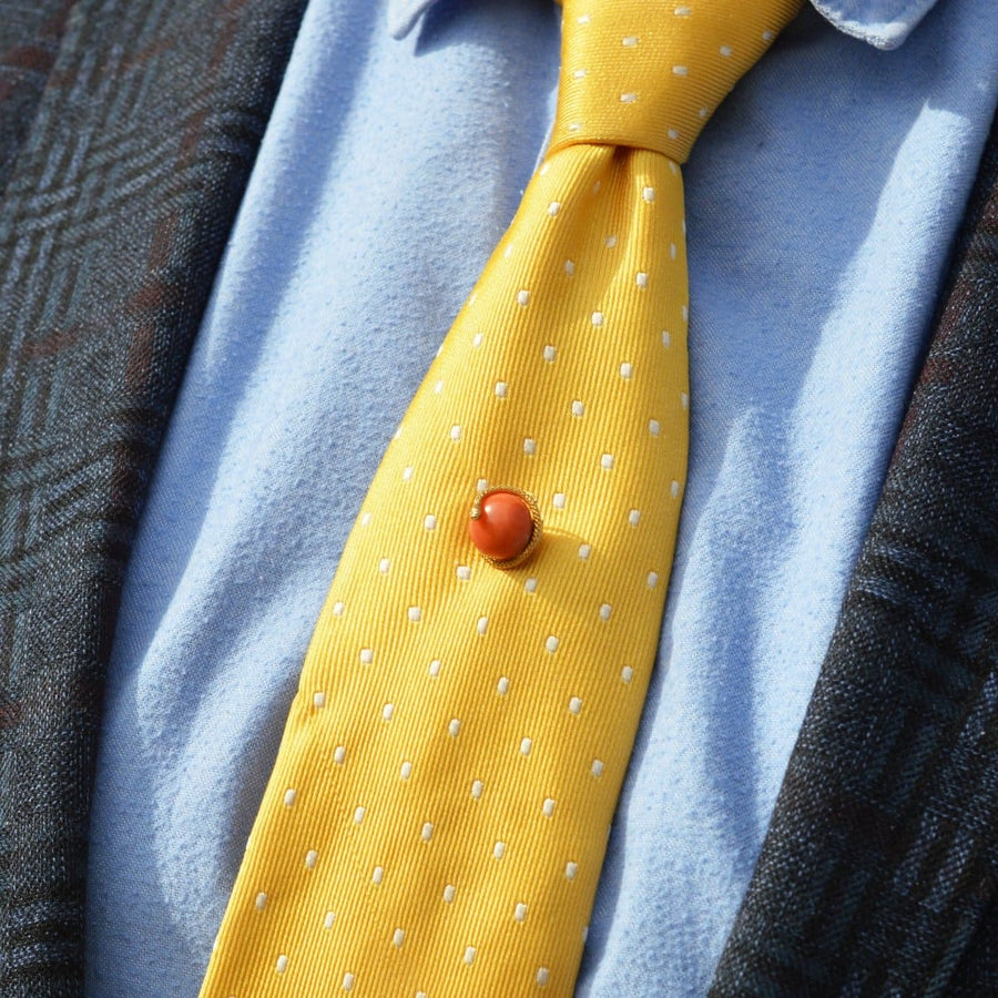 Victorian 15ct gold snake tie pin with coral bead, worn on a yellow polka dot tie, symbolizing everlasting love.