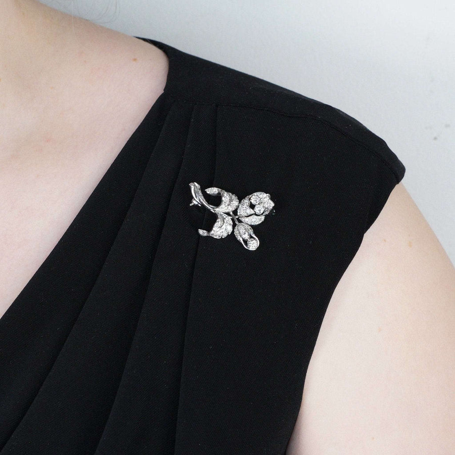 1950s diamond flower spray brooch in 18ct white gold worn on a black dress, showcasing exquisite craftsmanship.