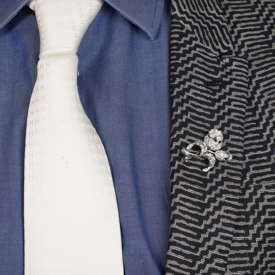 Elegant 1950s white gold diamond flower brooch worn on a suit jacket with a white tie.