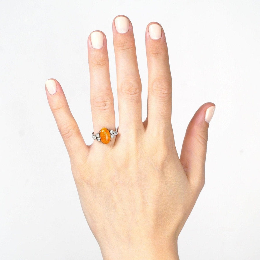 Hand wearing a vintage 1960s Boodles platinum ring with a fire opal and diamond accents.