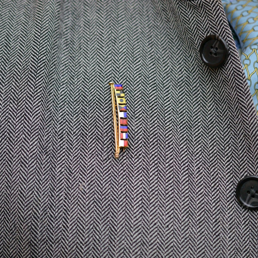 1970s vintage 9ct gold nautical signal flag brooch spelling Elizabeth on a patterned blazer.