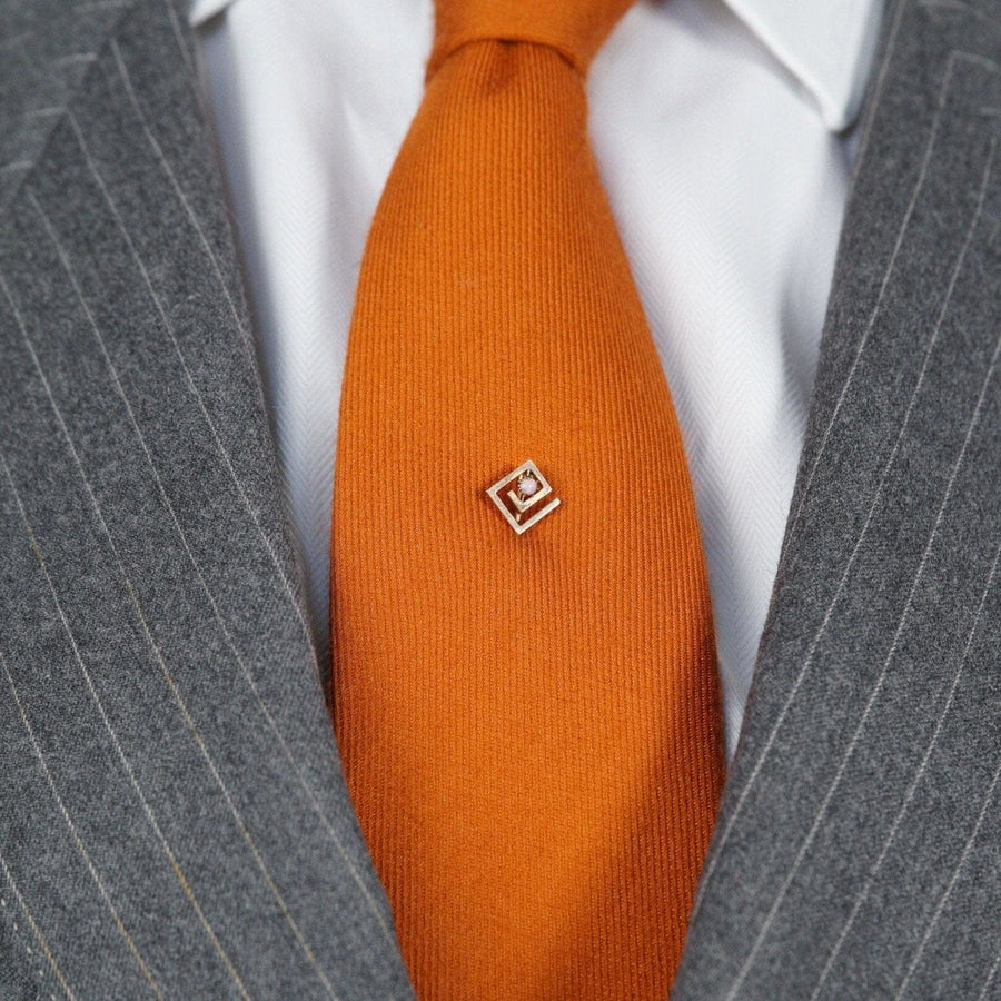 Art Deco gold and opal geometric tie pin on stylish orange silk tie, perfect for formal occasions.
