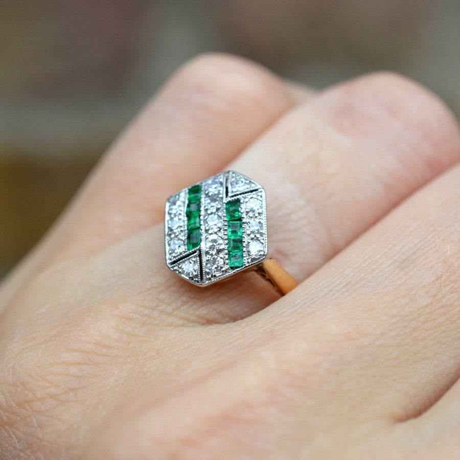 Art Deco 18ct gold and platinum hexagonal ring with emeralds and diamonds worn on a finger.