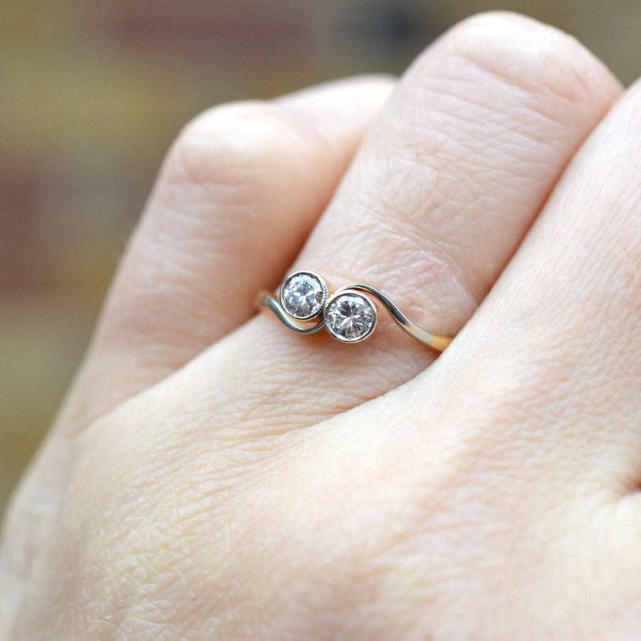 Art Deco 18ct gold and platinum 'Toi et Moi' diamond crossover ring on hand, symbolizing love and unity.