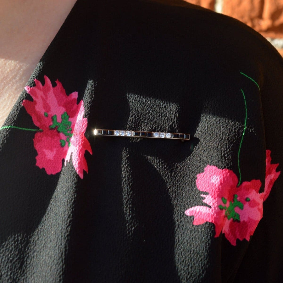 Art Deco platinum onyx bar brooch with diamonds on a floral dress lapel.