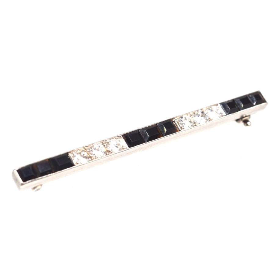 Art Deco platinum onyx bar brooch featuring emerald cut onyx and round diamonds, perfect for lapel or hat.