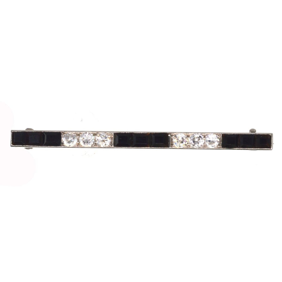 Art Deco platinum bar brooch featuring emerald cut onyx and round diamonds, perfect for any stylish accessory.