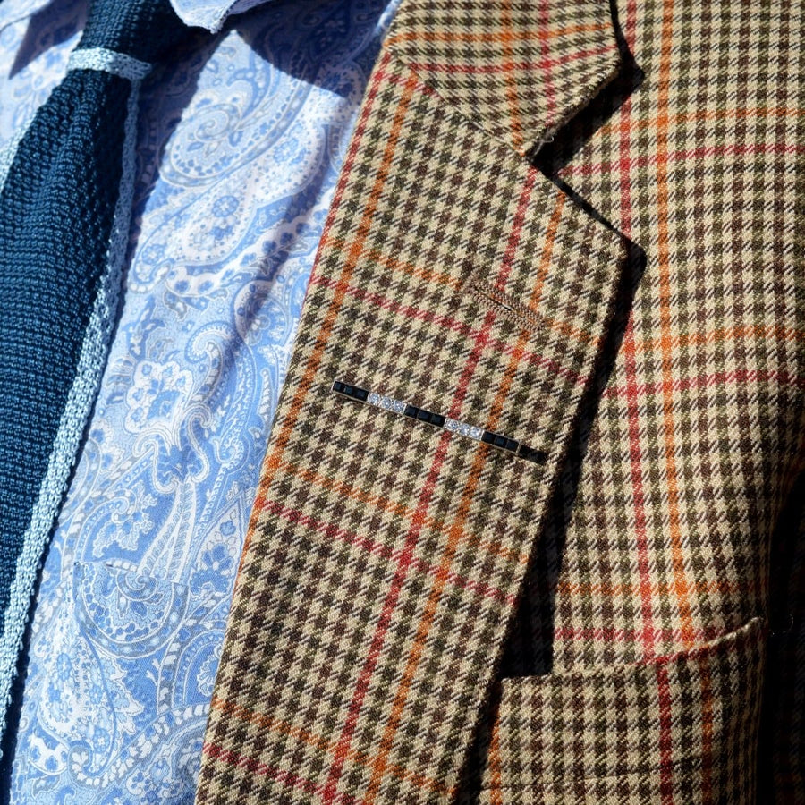 Close-up of a patterned blazer with a tie, showcasing a stylish lapel detail.