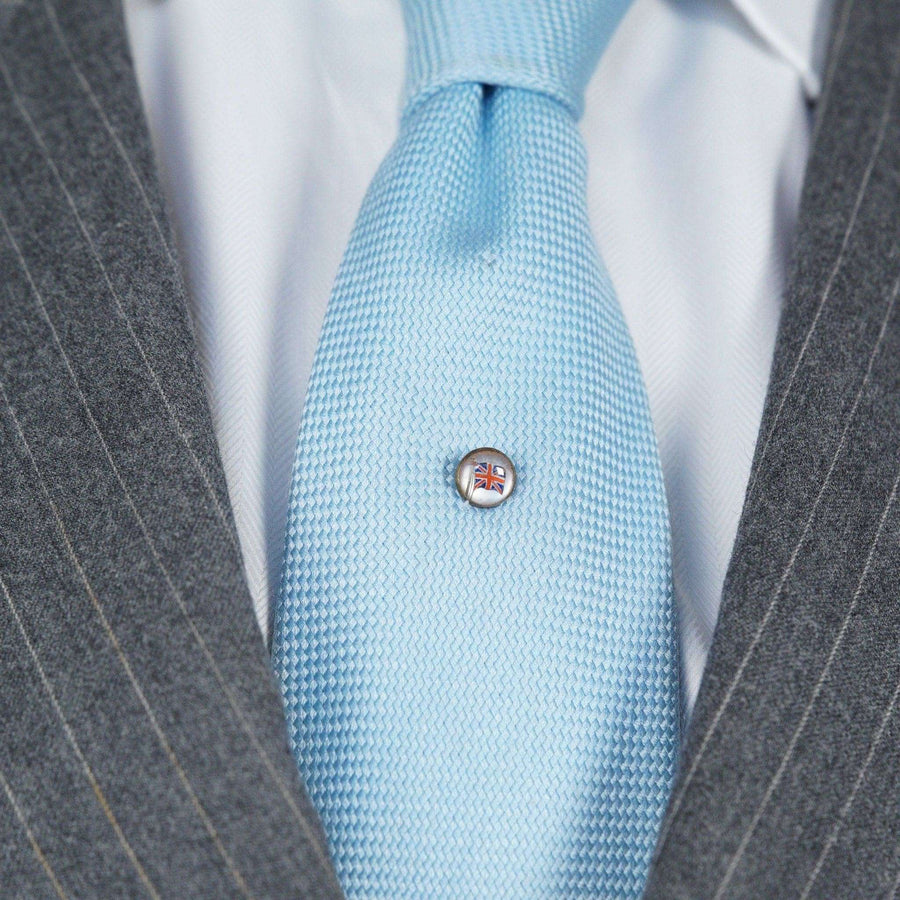Art Deco reverse intaglio paste tie pin featuring British Flag on light blue tie and gray suit.