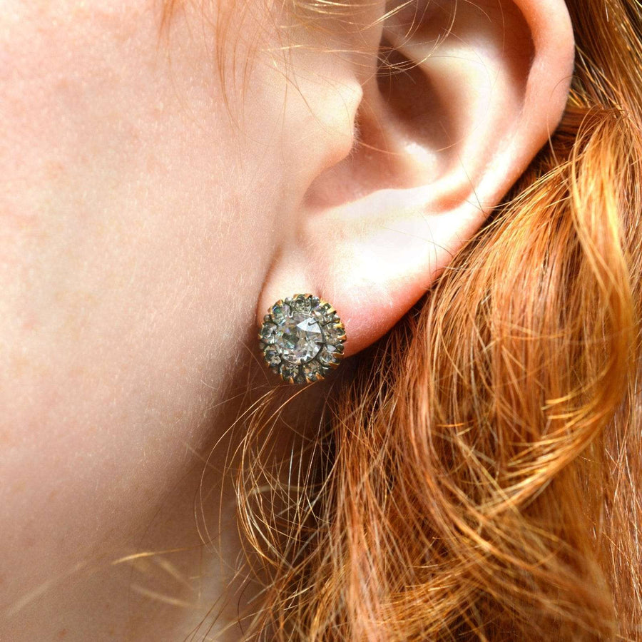 Art Deco silver and 9ct gold cluster earrings featuring white paste stones, elegantly worn on a model's ear.