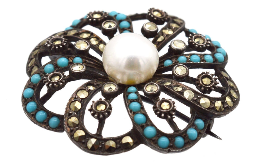 Art Deco silver brooch featuring turquoise, marcasite embellishments, and a central large cultured pearl from the 1930s.