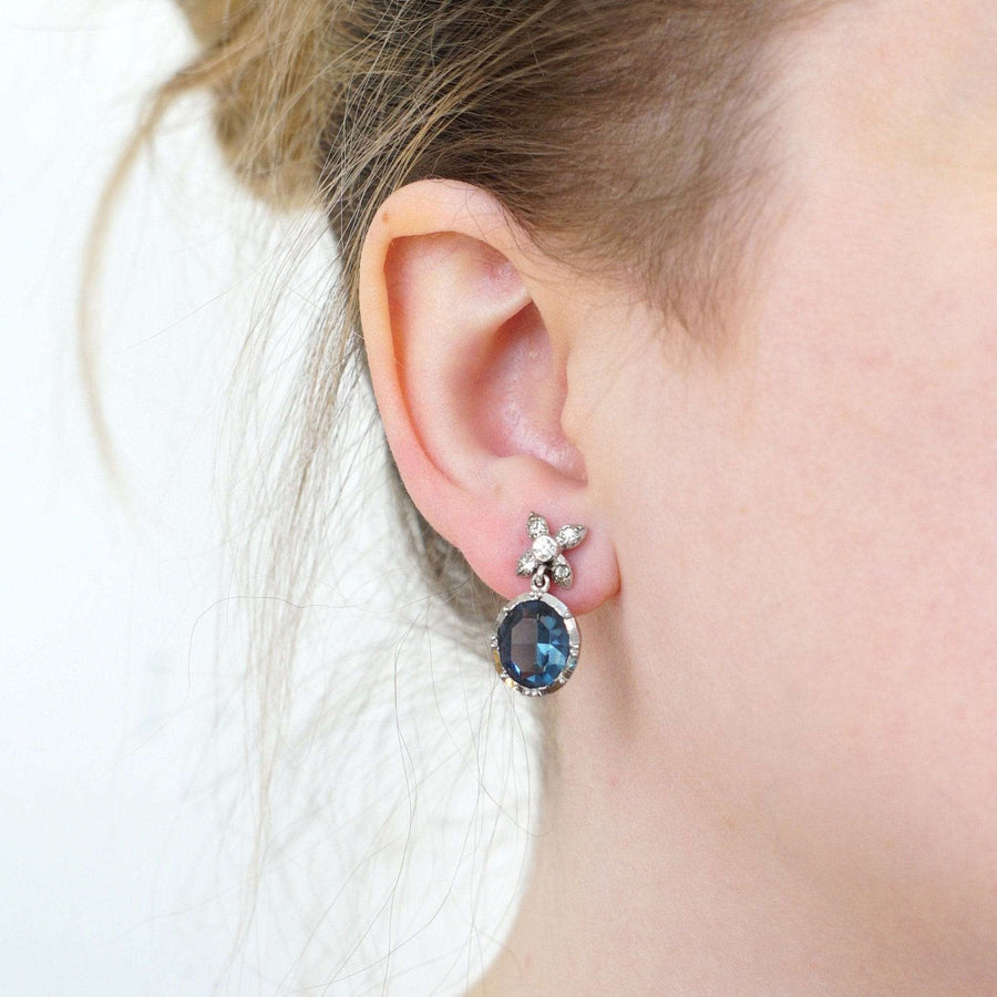 Art Deco silver earrings with blue paste stones and diamond accents, worn by a model.