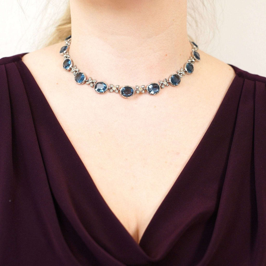 Art Deco silver necklace with blue sapphire paste and diamond paste links, worn elegantly on a woman's neck.