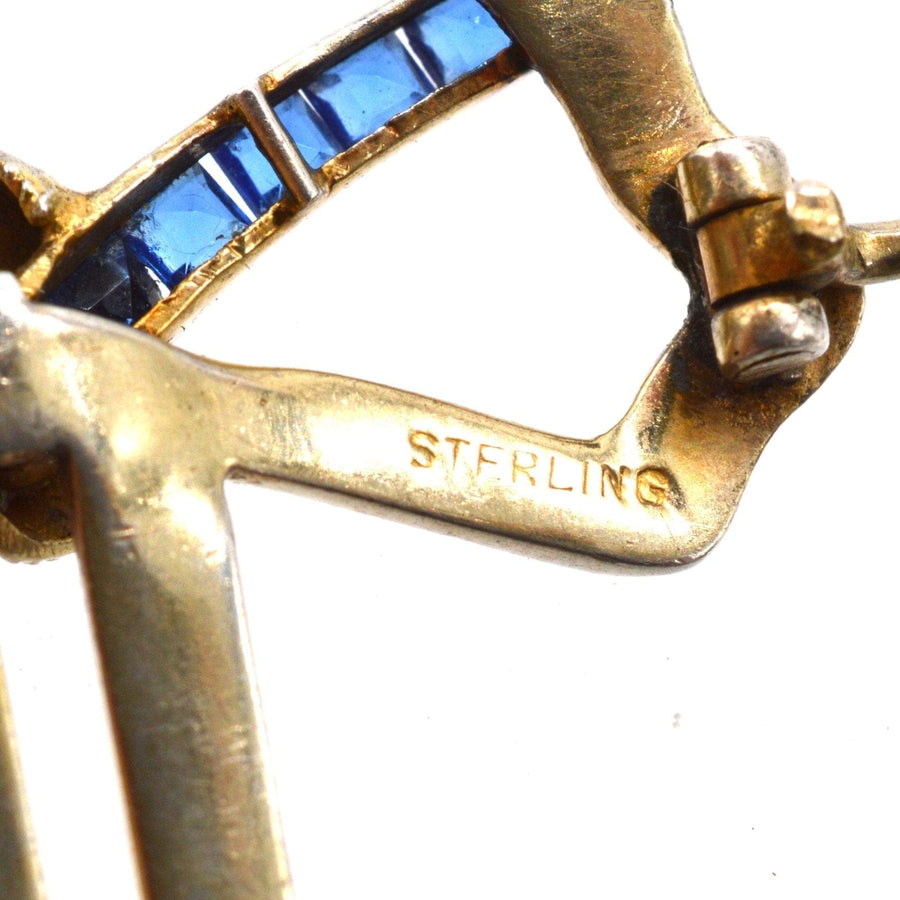 Close-up of Art Deco brooch showing sterling silver base with blue paste stones and intricate detailing.