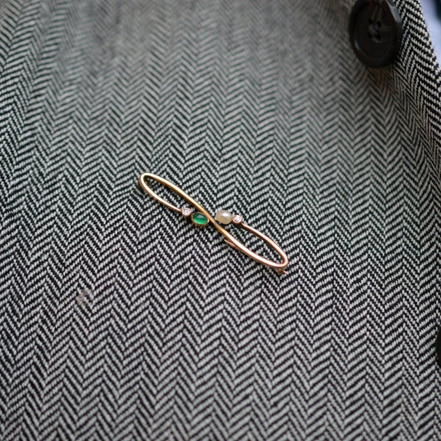 Art Nouveau 15ct gold brooch featuring cabochon emerald, pearl, and diamond on herringbone fabric.