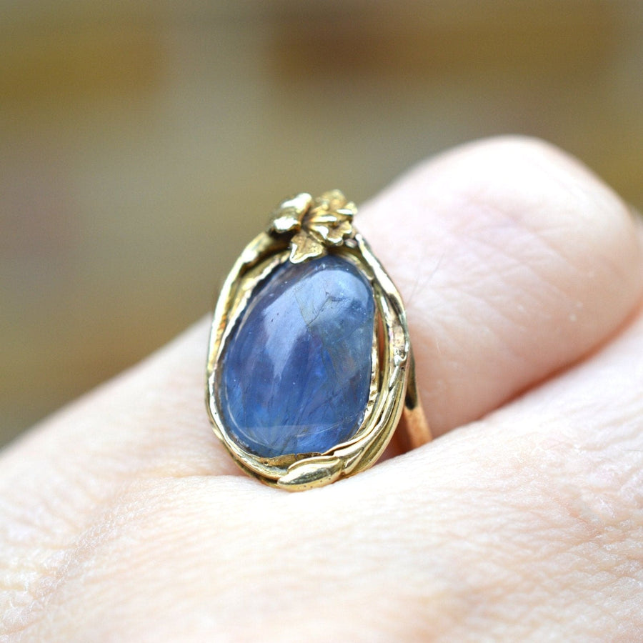 Art Nouveau 18ct gold ring featuring a large cabochon kyanite gemstone, surrounded by floral design.