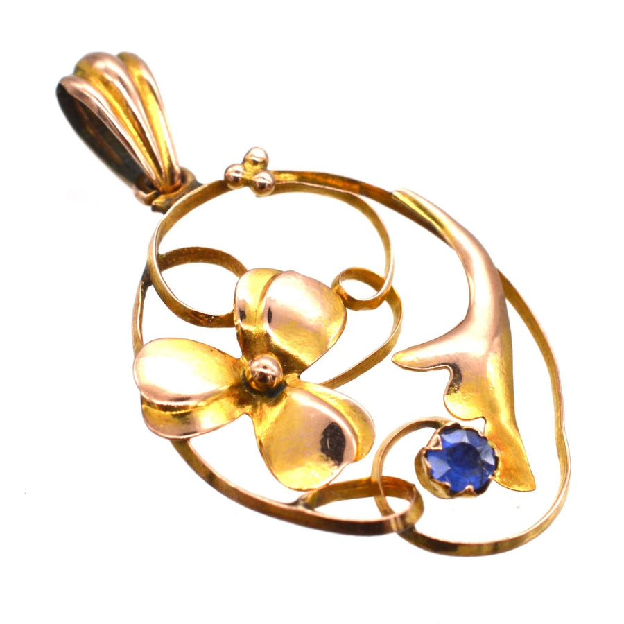 Art Nouveau 9ct gold floral pendant featuring a sapphire, showcasing a delicate flower design.