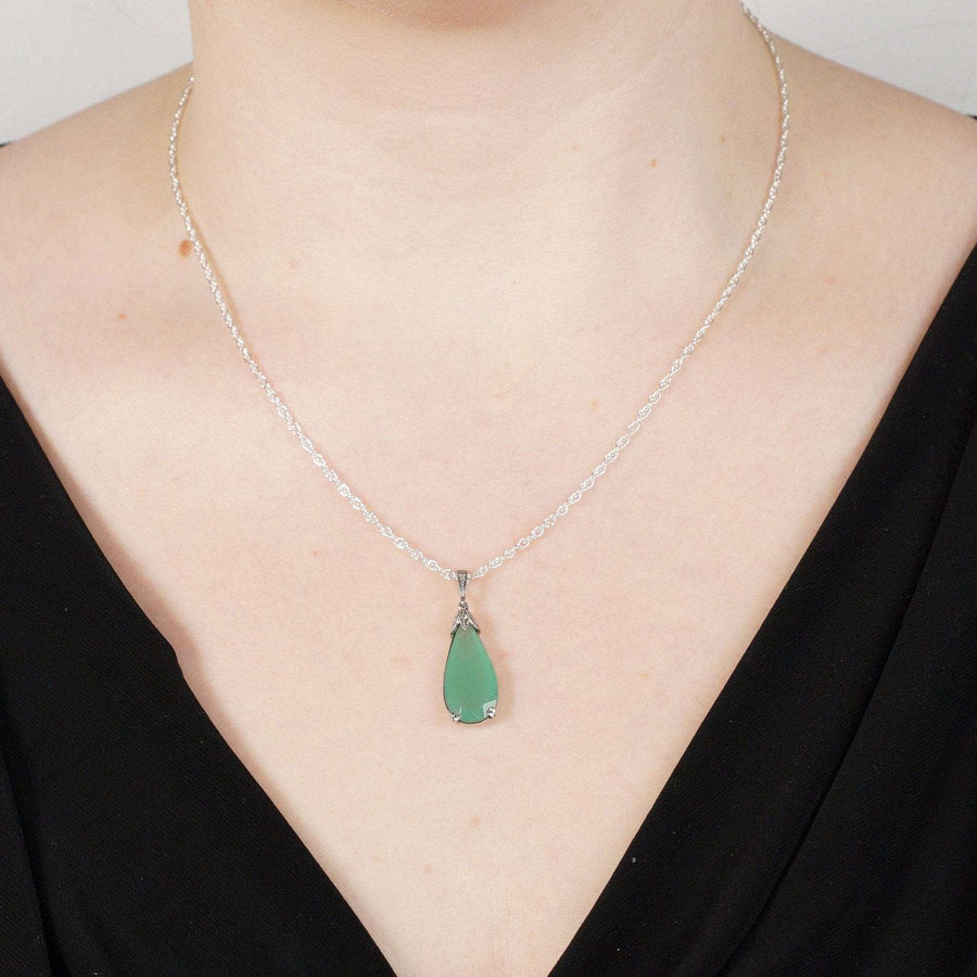 Elegant silver necklace with green teardrop pendant worn by a model.