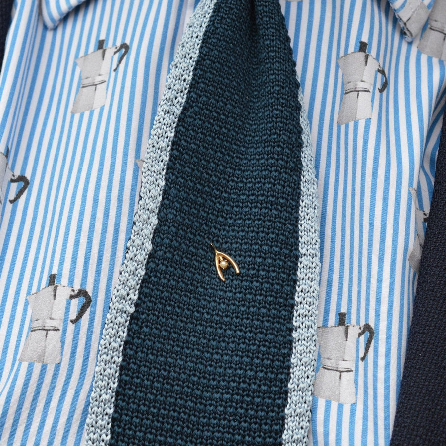 Edwardian 15ct gold wishbone tie pin on a knitted tie, symbolizing luck and style, paired with a patterned shirt.