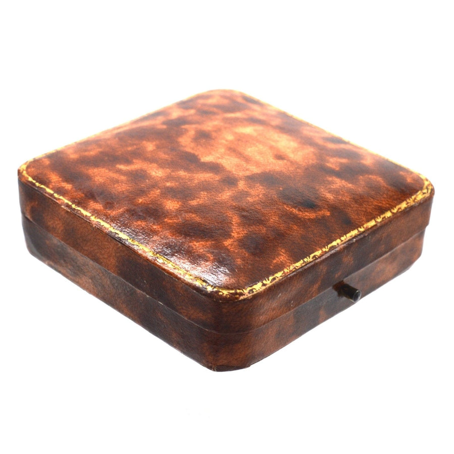 Antique brown leather jewellery box with a textured finish and gold trim on the edges.