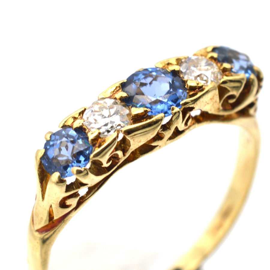 Elegant Edwardian 15ct gold ring featuring three cornflower blue sapphires and two sparkling diamonds in a half hoop design.