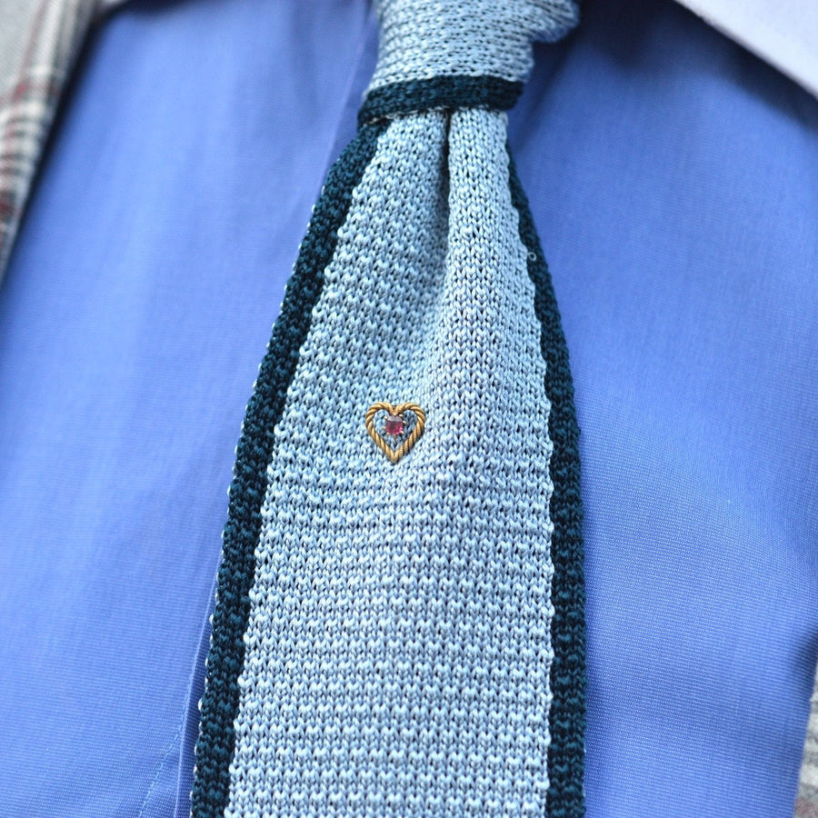 Edwardian 15ct gold knot heart tie pin with a ruby accent on a stylish blue knitted tie.