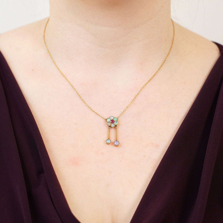 Edwardian 15ct gold pendant featuring ruby and opal clusters, worn on a model's neck, showcasing antique jewelry elegance.