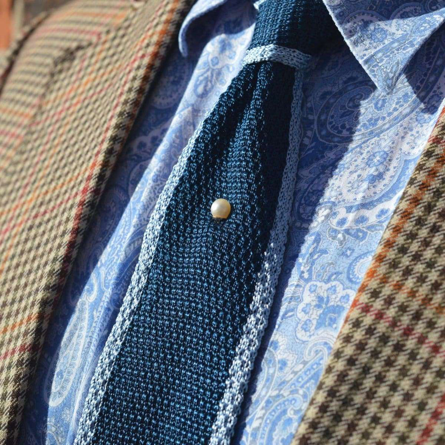 Close-up of a tie featuring a natural saltwater pearl tie pin, styled with an Edwardian-inspired outfit.