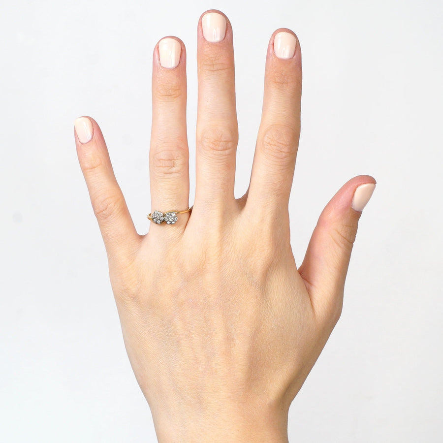 Hand wearing an Edwardian 18ct gold diamond cluster crossover ring, showcasing delicate floral design.