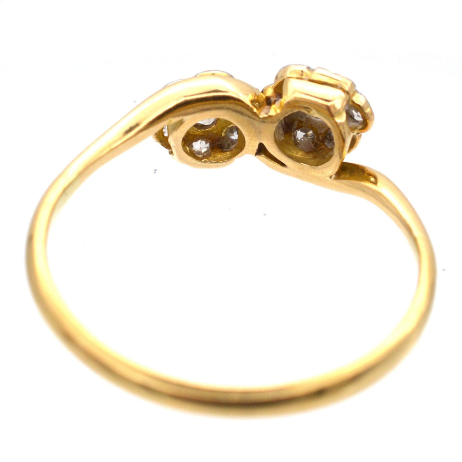 Close-up of Edwardian 18ct gold crossover ring featuring two diamond flowers, symbolizing love and elegance.