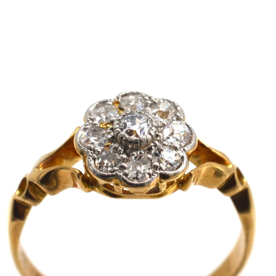 Edwardian 18ct gold cluster ring featuring old mine cut diamonds in a flower shape with decorated shoulders.