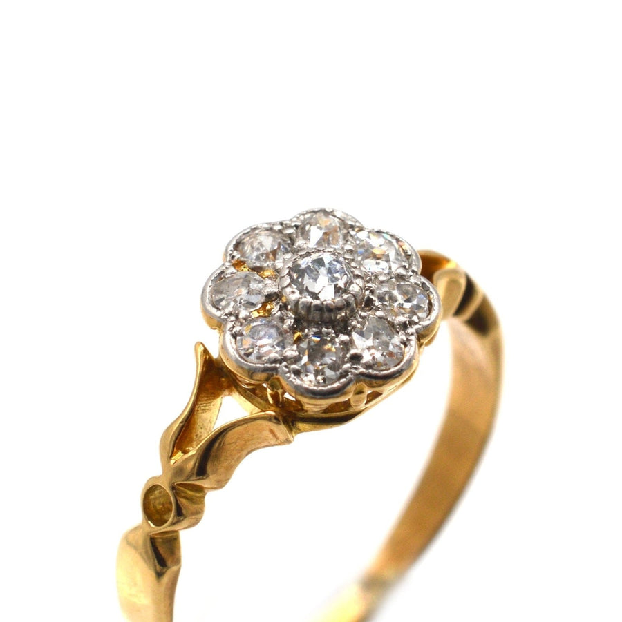 Edwardian 18ct gold cluster ring featuring old mine cut diamonds in flower shape with decorated shoulders.