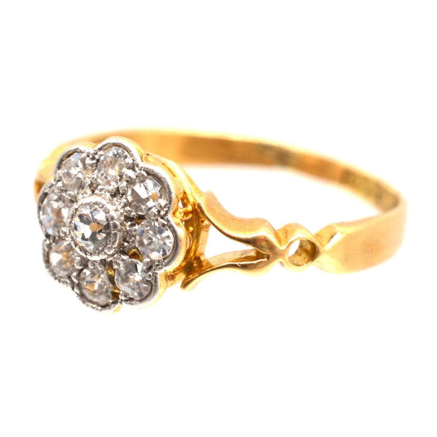 Edwardian 18ct gold cluster ring featuring old mine cut diamonds in a floral design with decorated shoulders.