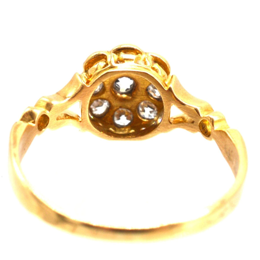 Edwardian 18ct gold old mine cut diamond cluster ring featuring decorated shoulders and flower-shaped diamond setting.
