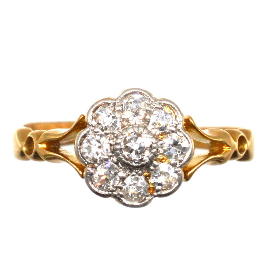 Edwardian 18ct gold cluster ring featuring old mine cut diamonds in a floral design with decorated shoulders.