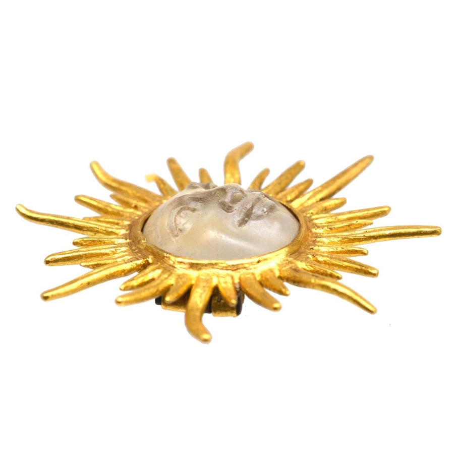 Edwardian brooch featuring opalescent glass man in the moon amid a golden sunburst design, circa 1910s.