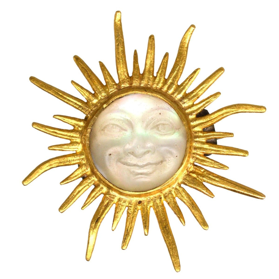 Edwardian 18ct gold opalescent glass sunburst brooch featuring a smiling man in the moon, circa 1910s.