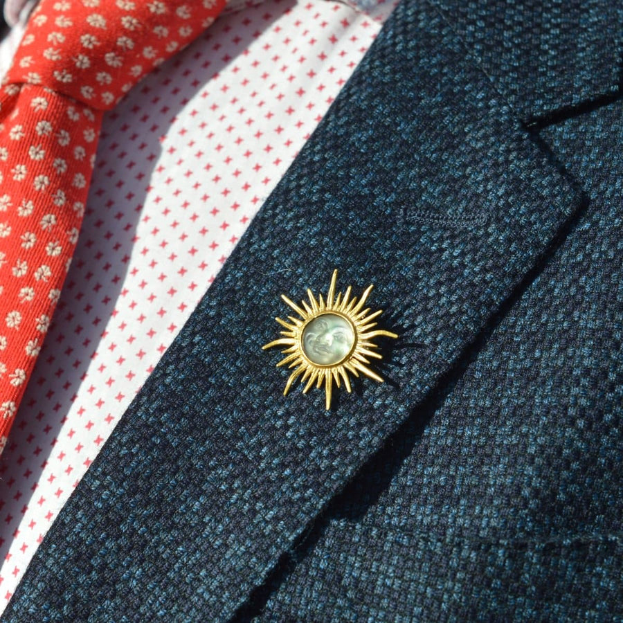 Edwardian 18ct gold sunburst brooch with opalescent glass, worn on lapel, showcasing vintage elegance.