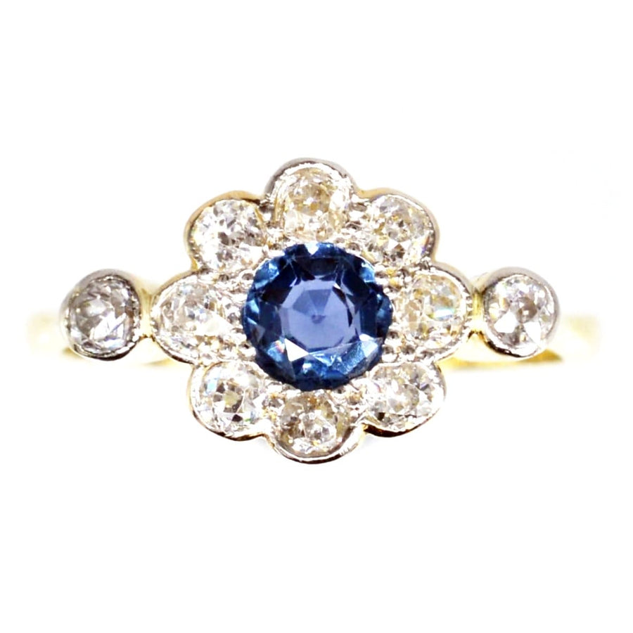Edwardian 18ct gold and platinum sapphire and diamond cluster ring, featuring a central blue sapphire surrounded by diamonds.