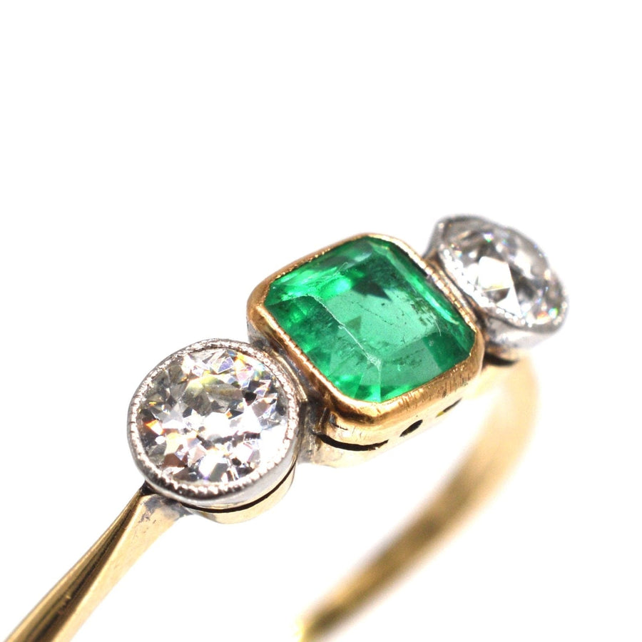 Edwardian 18ct gold and platinum three stone ring with vibrant green emerald and dazzling diamonds.