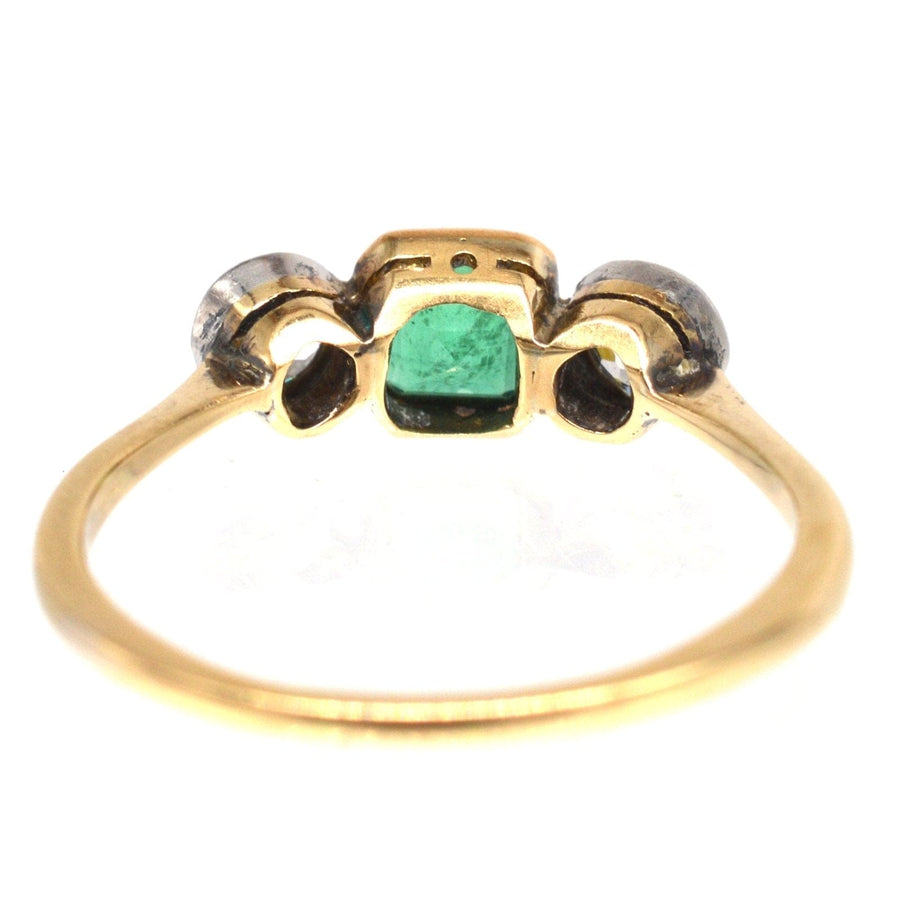 Edwardian 18ct gold and platinum three stone emerald and diamond ring, featuring vibrant green emerald centerpiece and diamond accents.