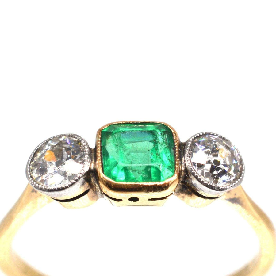 Edwardian 18ct gold and platinum three stone emerald and diamond ring with vibrant green emerald center.