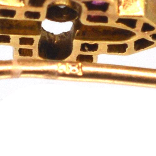 Close-up view of the hallmark on an Edwardian 18ct gold ruby and diamond tie pin, showcasing fine craftsmanship.