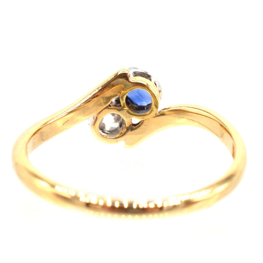 Edwardian 18ct gold crossover ring featuring a sapphire and diamond, symbolizing romantic connection.
