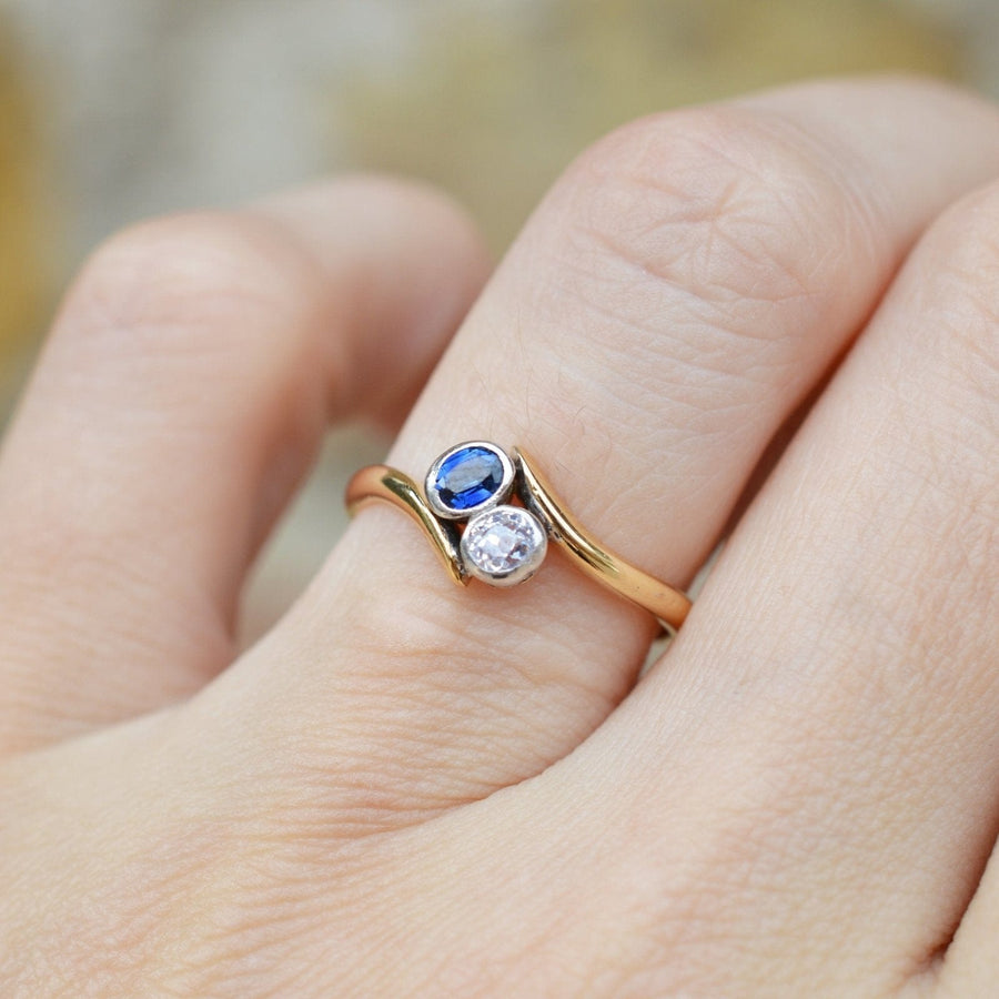 Edwardian 18ct gold crossover ring featuring sapphire and diamond, symbolizing love and connection.